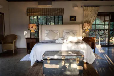 a bedroom with a bed with a trunk on the floor at Jabulani Bushhouse - Marlothpark in Marloth Park