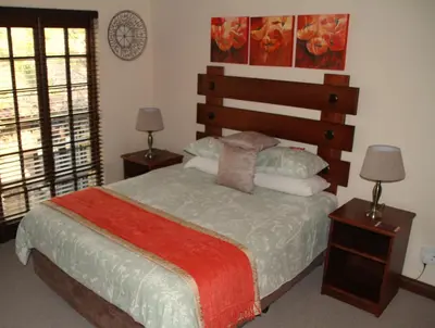a bedroom with a bed with two lamps and a window at White River Country Estate Self Catering Apartment in White River