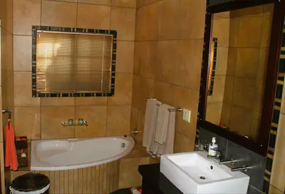 a bathroom with a tub and a sink at White River Country Estate Self Catering Apartment in White River