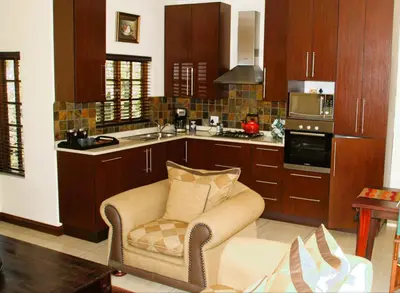 a kitchen with wooden cabinets and a chair in a room at White River Country Estate Self Catering Apartment in White River