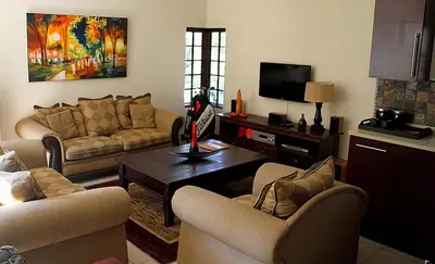 a living room with two couches and a tv at White River Country Estate Self Catering Apartment in White River