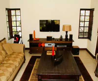 a living room with a couch and a tv at White River Country Estate Self Catering Apartment in White River