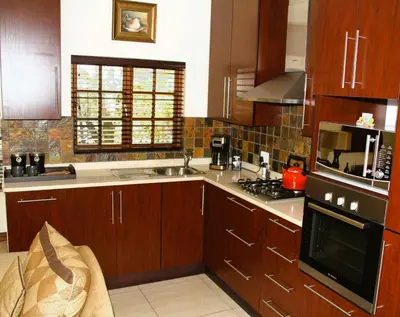 a kitchen with wooden cabinets and a stove top oven at White River Country Estate Self Catering Apartment in White River