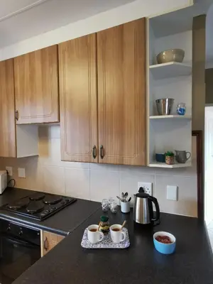 a kitchen with wooden cabinets and a counter top at Private Apartment for business and leisure Pretoria East in Pretoria