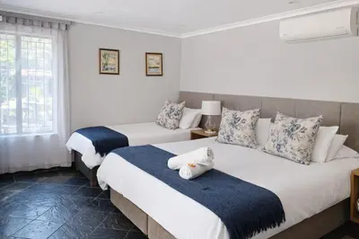 two beds in a room with white walls and windows at Magalies Mountain Lodge and Spa in Hartbeespoort