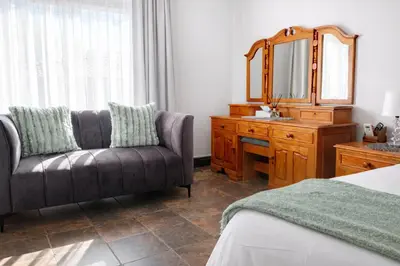 a bedroom with a couch and a mirror and a dresser at Magalies Mountain Lodge and Spa in Hartbeespoort