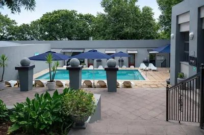 a swimming pool with blue umbrellas and chairs at Magalies Mountain Lodge and Spa in Hartbeespoort