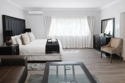 a bedroom with a bed and a couch and a glass table at Magalies Mountain Lodge and Spa in Hartbeespoort