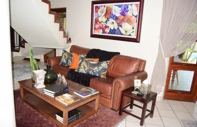 a living room with a brown leather couch and tables at Tengo guest house in Phalaborwa