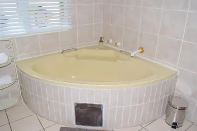 a bath tub in a bathroom with a sink at Tengo guest house in Phalaborwa
