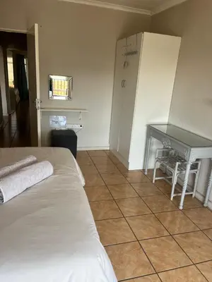 a room with a bed and a refrigerator and a table at La Prima Casa in Graskop