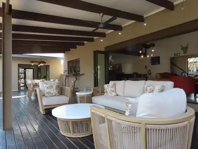 a living room with white couches and a table and chairs at Wildheart Safari - MAIN in Hoedspruit