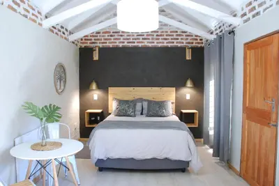 a bedroom with a large bed and a white table at The Stables At Critchley in Dullstroom