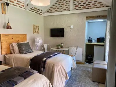 a bedroom with two beds and a table and a tv at The Stables At Critchley in Dullstroom