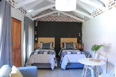 a bedroom with two beds and a table at The Stables At Critchley in Dullstroom
