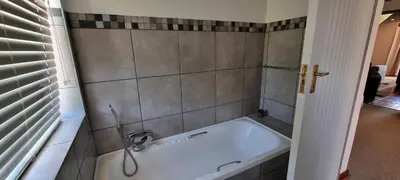 a bath tub in a bathroom with a tiled wall at DullVino Cottage no 15 at Critchley in Dullstroom