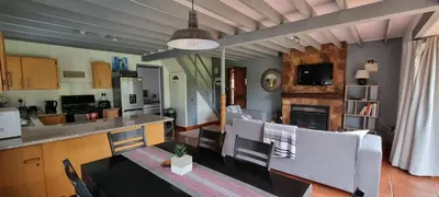 a kitchen and a living room with a table and chairs at DullVino Cottage no 15 at Critchley in Dullstroom