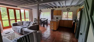 a living room and kitchen with a couch and a table at DullVino Cottage no 15 at Critchley in Dullstroom