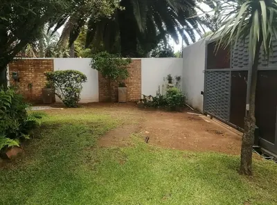 a yard with a white wall and a fence at 394OnEmus in Pretoria