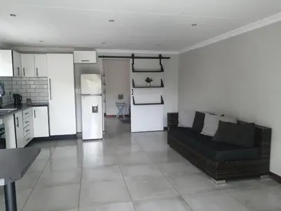 a living room with a couch and a kitchen at 394OnEmus in Pretoria