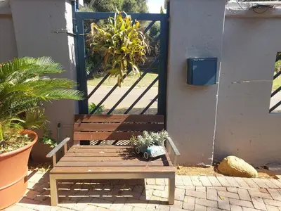 a wooden bench in front of a door with plants at Garrett B&B in Pretoria