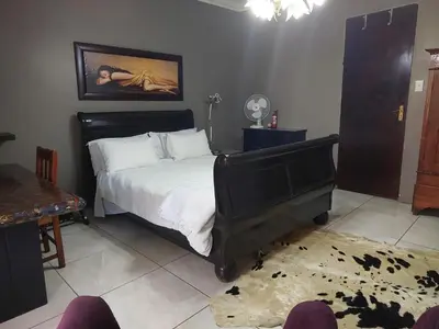 a bedroom with a large bed and a table at Garrett B&B in Pretoria