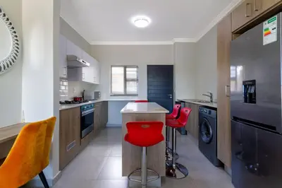 a kitchen with red chairs and a counter in it at Alimama Spaces: The Thando's Kyalami Woods in Midrand