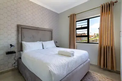 a bedroom with a large white bed with a window at Alimama Spaces: The Thando's Kyalami Woods in Midrand