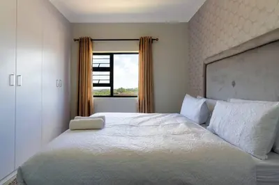a bedroom with a large white bed with a window at Alimama Spaces: The Thando's Kyalami Woods in Midrand