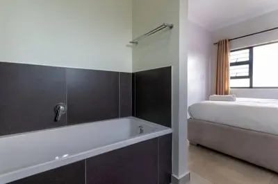 a bathroom with a bath tub next to a bed at Alimama Spaces: The Thando's Kyalami Woods in Midrand