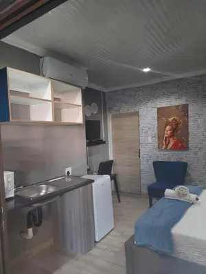 a room with a kitchen and a room with a bed at Nsuku Bed and Breakfast in Thulamahashi