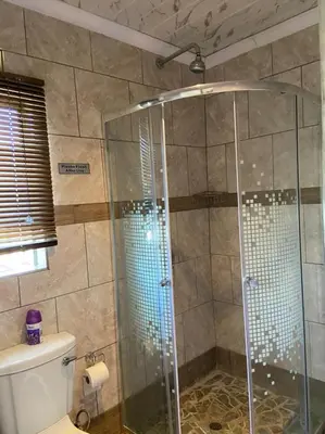 a shower with a glass door in a bathroom at Nsuku Bed and Breakfast in Thulamahashi