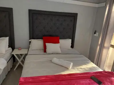 a bedroom with a large bed with a red pillow at Nsuku Bed and Breakfast in Thulamahashi