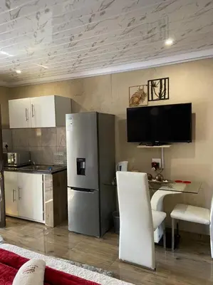 a kitchen with a stainless steel refrigerator and a table at Nsuku Bed and Breakfast in Thulamahashi