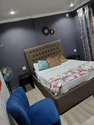 a bedroom with a bed and a blue chair at Nsuku Bed and Breakfast in Thulamahashi