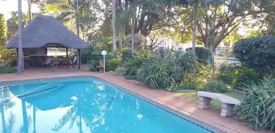 a swimming pool with a bench and a gazebo at Georeen Guest House in Polokwane