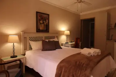 a bedroom with a white bed with two towels on it at Georeen Guest House in Polokwane