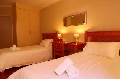 a bedroom with two beds and a desk with a mirror at Georeen Guest House in Polokwane