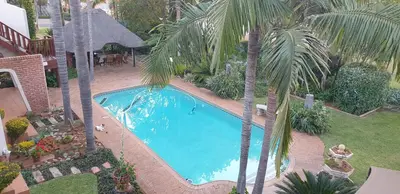 an overhead view of a swimming pool with palm trees at Georeen Guest House in Polokwane