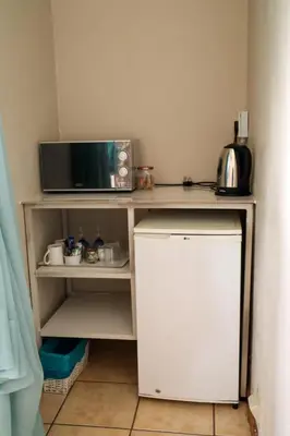 a small kitchen with a microwave and a small refrigerator at Georeen Guest House in Polokwane