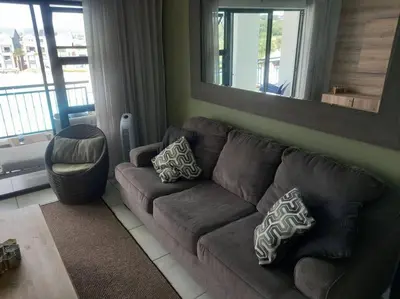a living room with a brown couch and a mirror at Breathtaking Lagoon View Apartment @ The Blyde1531 in Pretoria