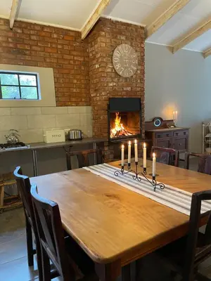 a dining room with a table and a fireplace at East of East Guest Cottage in Avondzon