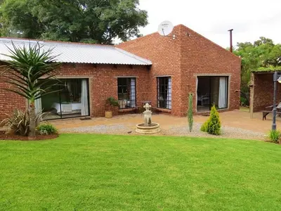 a brick house with a fountain in the yard at East of East Guest Cottage in Avondzon