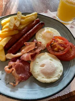 a plate of breakfast food with eggs bacon and french fries at East of East Guest Cottage in Avondzon