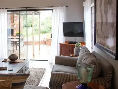 a living room with a couch and a television at East of East Guest Cottage in Avondzon