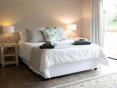 a bedroom with a white bed and a window at East of East Guest Cottage in Avondzon
