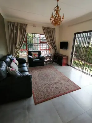 a living room with a couch and chairs and windows at Garden and Park Leisure on Tugela in Benoni