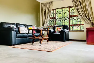 a living room with a black leather couch and a table at Garden and Park Leisure on Tugela in Benoni