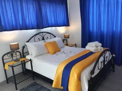 a bedroom with a large bed with blue curtains at 13th Avenue Guesthouse Benoni in Benoni