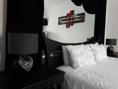 a bedroom with a bed and a table with a lamp at 13th Avenue Guesthouse Benoni in Benoni